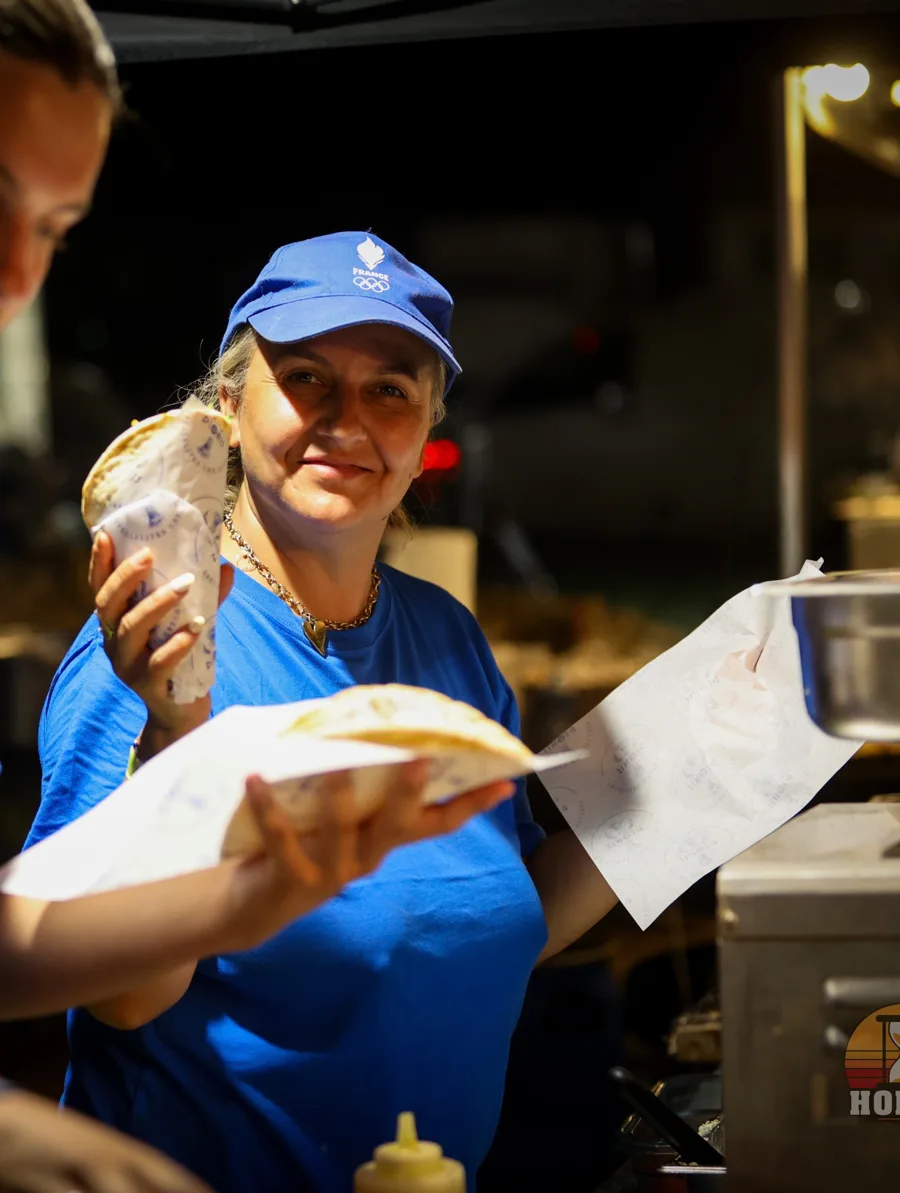 La femme du patron, souriante, une pita à la main au camion